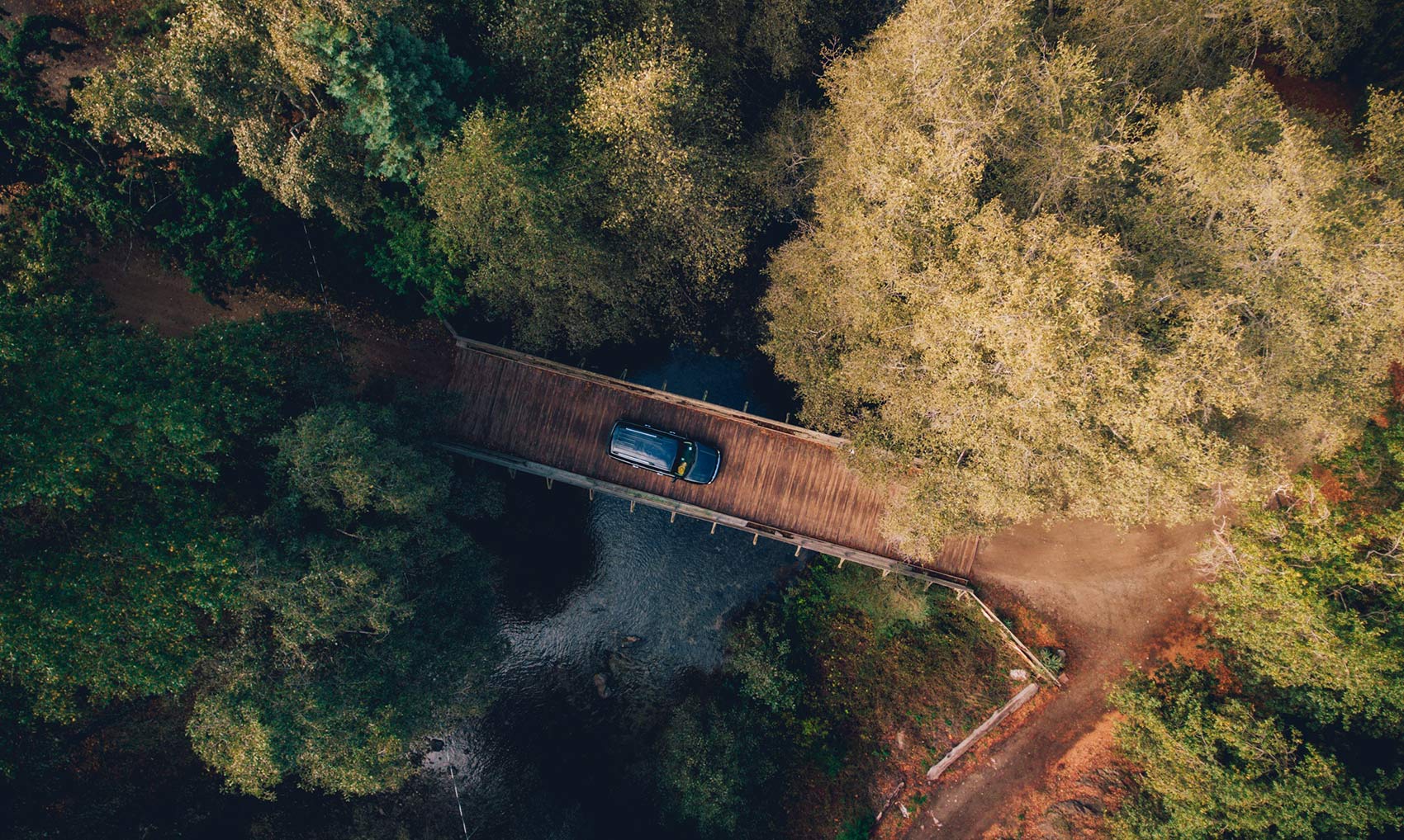 A car driving down the road near trees.