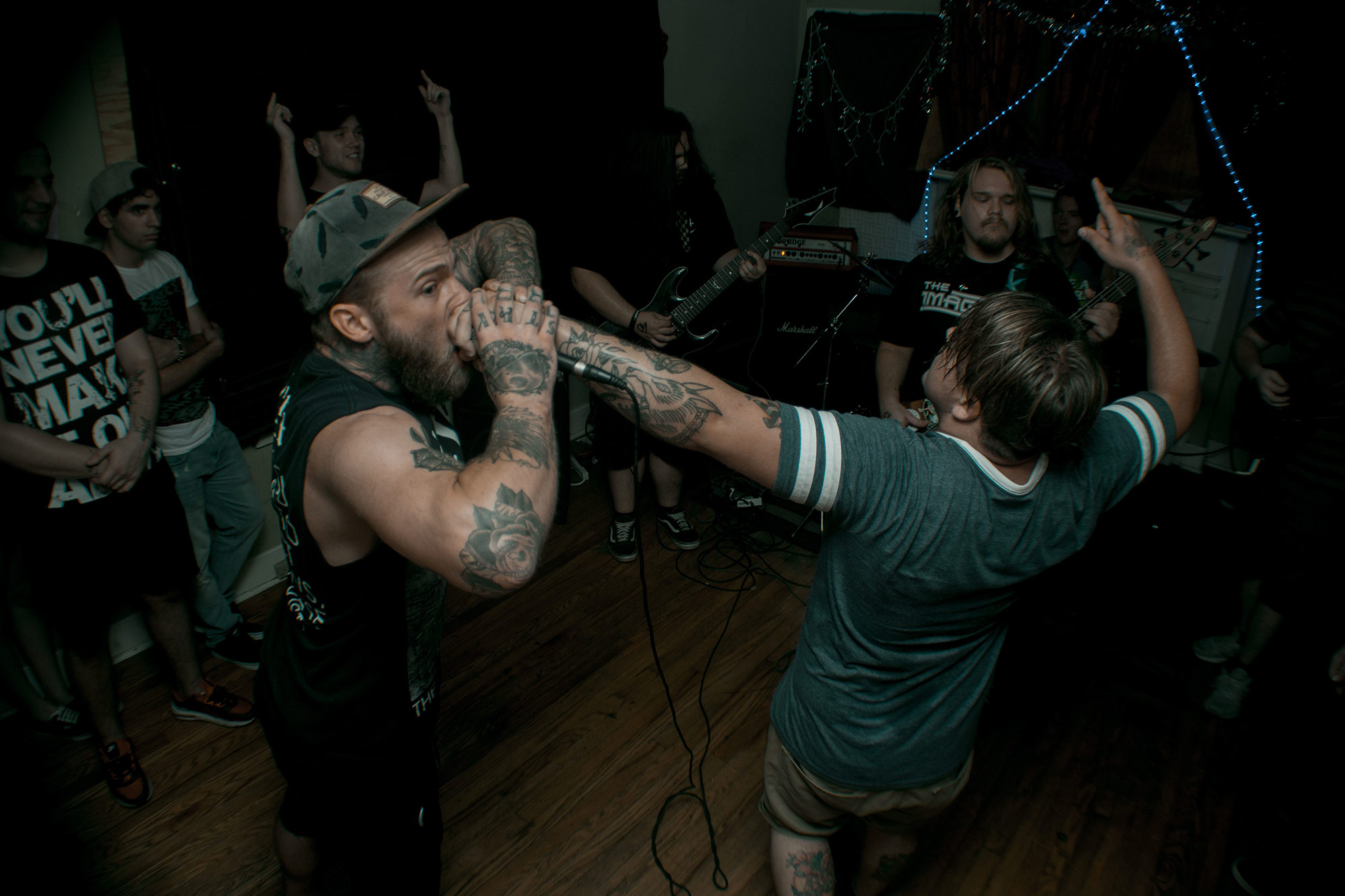 Two men are fighting in a room with people.