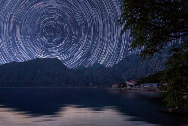 A star trail is shown over the water.