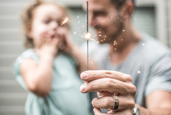 A man and child holding sparklers in their hands.