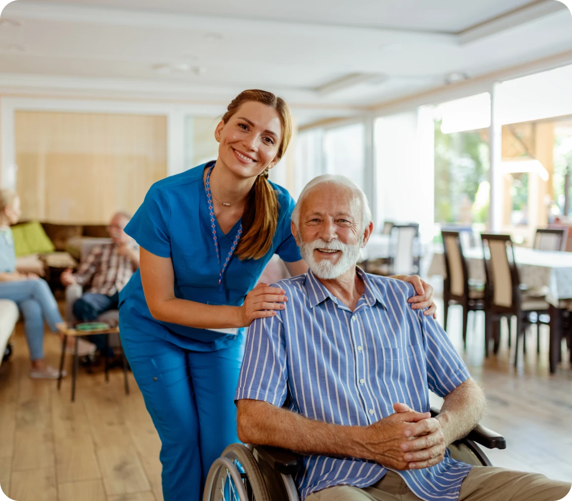 Nurse smiling with elderly man in wheelchair